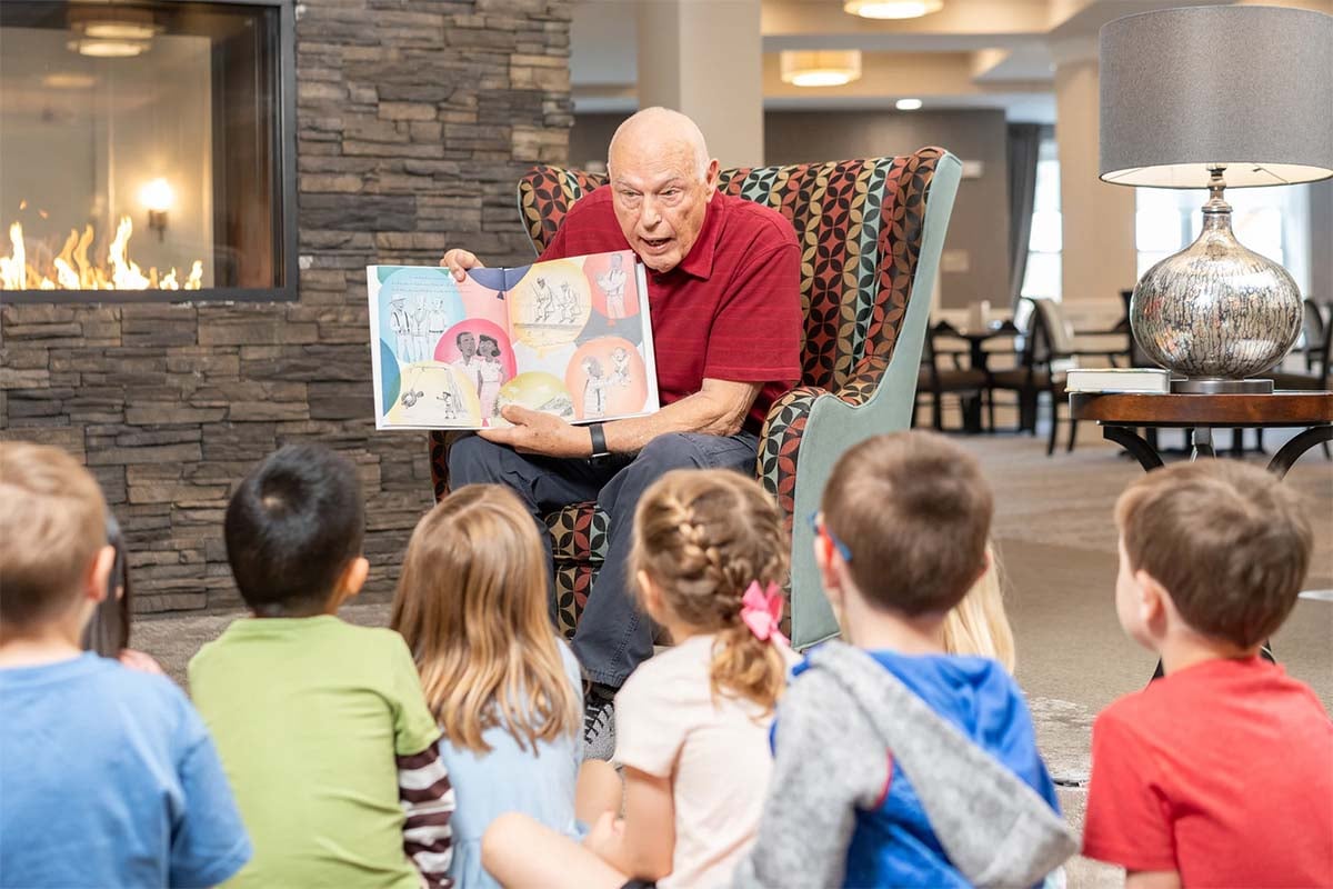 senior man reading a book to a group of young kids