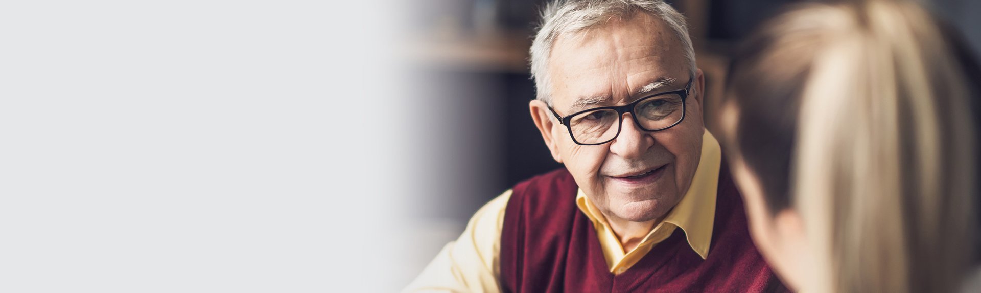 a senior man wearing glasses talking with a younger female