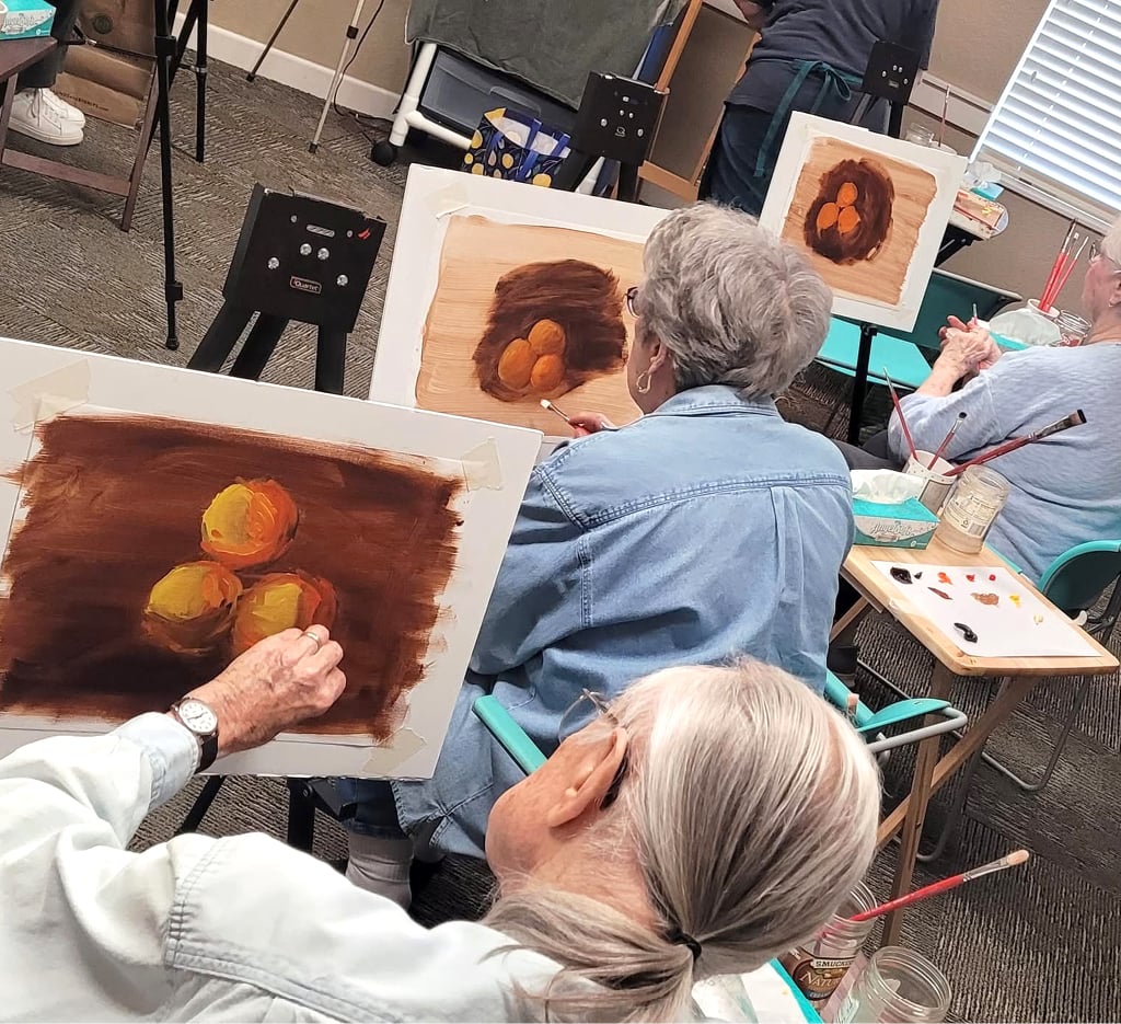 group of senior women painting on a canvas
