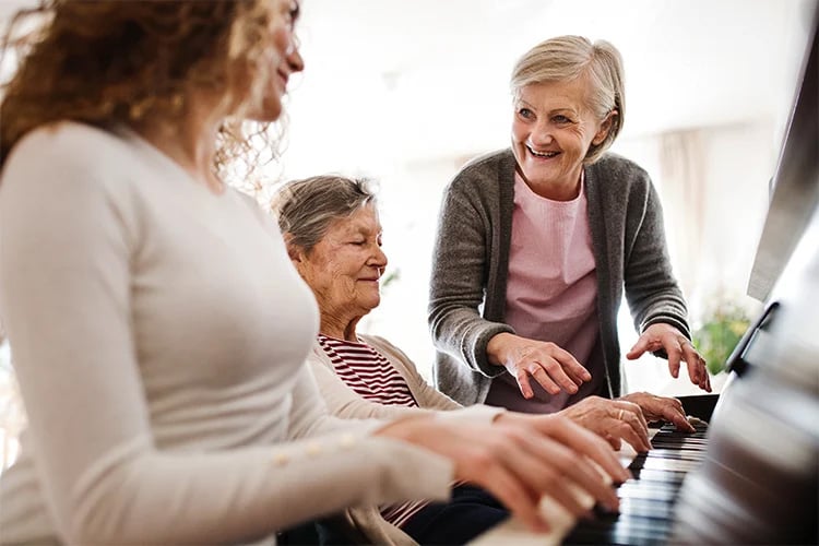 three women having fun playing the piano